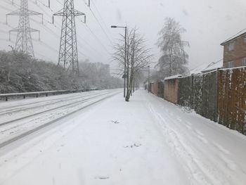 Snow covered railroad tracks against sky during winter