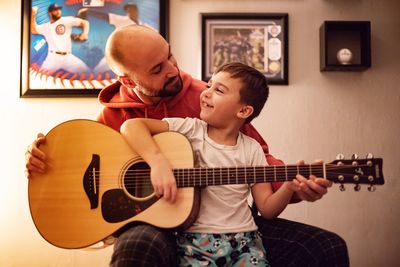 Boy with father playing guitar at home