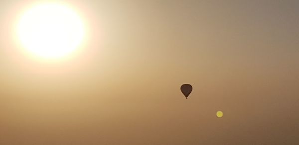 Low angle view of silhouette hot air balloon flying in sky during sunset