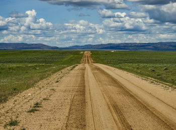 Road amidst field against sky