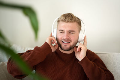 Portrait of young man listening to music at home with headphones 