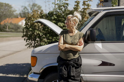 Woman standing in front of car