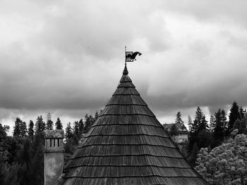 Low angle view of cross amidst trees and buildings against sky