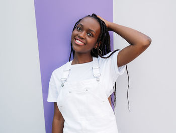 Portrait of young woman standing against blue background