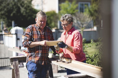 Senior couple examining wooden plank at yard