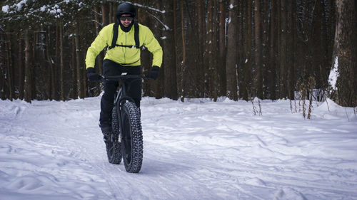 Man riding bicycle on snow covered field