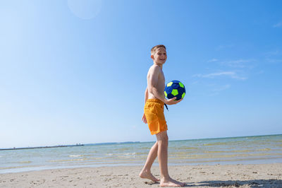 Full length of boy on beach against sky