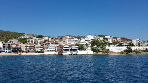 Houses by sea against clear blue sky