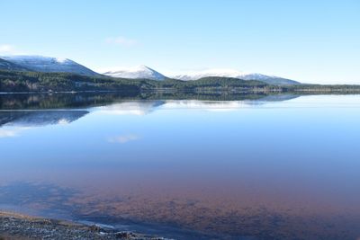 Scenic view of lake by mountains against sky