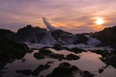 Scenic view of rocks in sea against sky during sunset