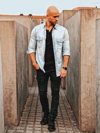 Full length portrait of young man standing against wall