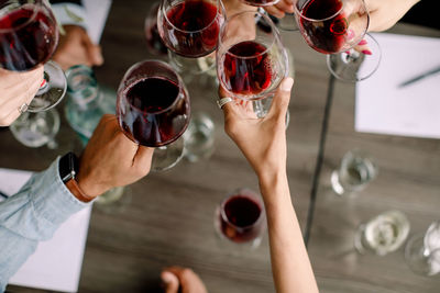 Cropped image of businessmen and businesswomen toasting wineglasses over table at convention center