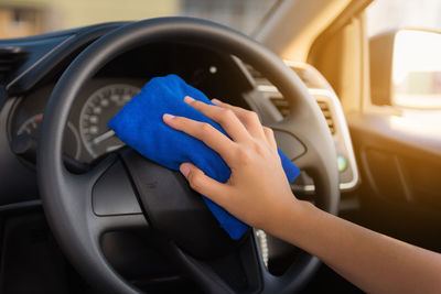 Cropped hand of woman cleaning car steering wheel
