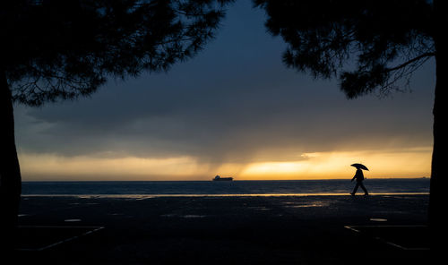 Silhouette person standing on beach against sky during sunset