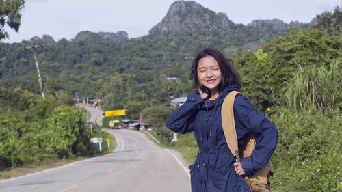 Portrait of smiling young woman standing on road