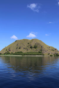 Scenic view of lake by mountain against blue sky