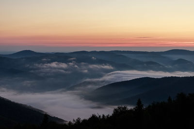 Scenic view of silhouette mountains against orange sky