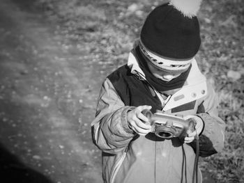 High angle view of boy holding camera on field