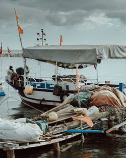 Fishing boats moored in sea against sky