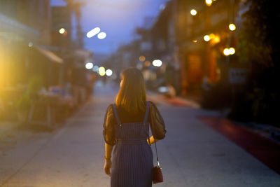 Rear view of woman walking on street at night