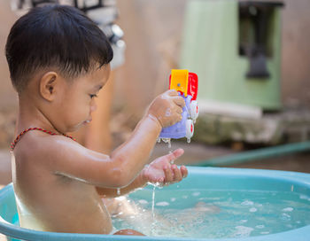 Close-up of shirtless bathing in bucket