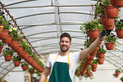Portrait of smiling young man standing in greenhouse
