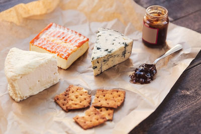 High angle view of cheese with crackers and preserves on table