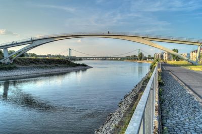 Bridge over river in city against sky