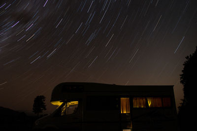 Low angle view of travel trailer against star trails