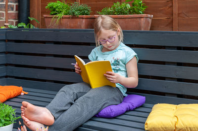 Little girl sitting in garden and doing prep work for her school.