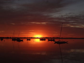 Silhouette sailboats in sea against dramatic sky during sunset