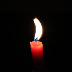 Close-up of burning candle against black background