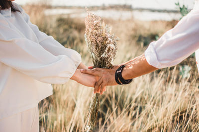 Wedding couple holding flowers while standing on grassy field