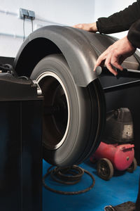 Cropped hands of mechanic with tire in machine at auto repair shop