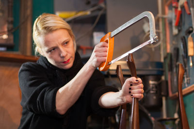 Woman with saw cutting wood