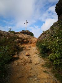 Low angle view of cross amidst rocks against sky