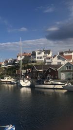 Sailboats moored in harbor against buildings in city