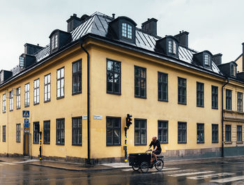 People riding motorcycle on street against buildings in city