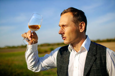 Man looking at wine glass in farmland