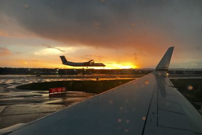 Airplane flying over sea against sky during sunset