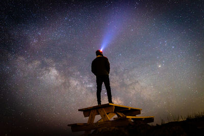 Rear view of man standing against sky at night