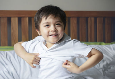 Portrait of cute boy smiling on bed at home
