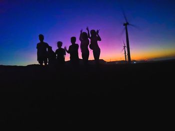 Silhouette people standing on land against sky during sunset