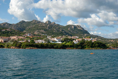 Scenic view of town by sea against sky