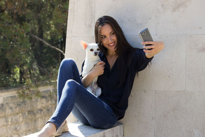 Young woman using mobile phone while sitting in camera