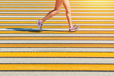 Woman running crosswalk, copy space. female jogging in sportswear on city road. street workout