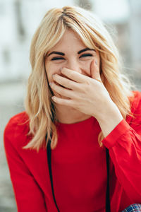 Portrait of cheerful young woman covering mouth