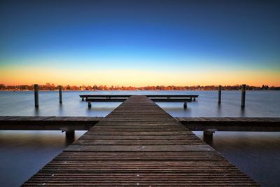 Pier over lake against clear sky during sunset