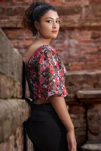 Portrait of woman standing against wall