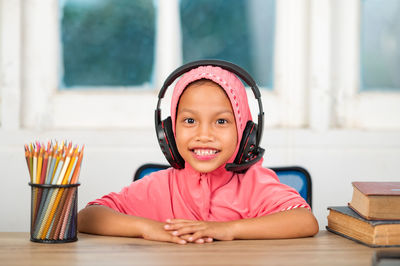 Portrait of a smiling girl sitting on table